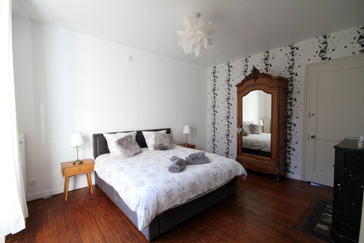 Une chambre à coucher comprenant un lit, une table de chevet, un miroir et une armoire.