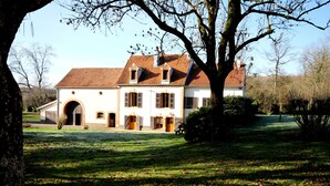 Un grand bâtiment blanc, doté d’un toit recouvert de tuiles rouges, de nombreuses fenêtres et d’une entrée centrale.