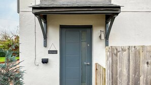 A front door with a dark-colored door, a small mailbox, and a welcome mat. - A lovely modern annexe nestled in the village of Guilsfield. (Guilsfield)