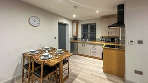 A modern kitchen with wooden cabinets, a built-in microwave, and a black range hood. - A lovely modern annexe nestled in the village of Guilsfield. (Guilsfield)