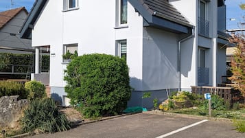 Een modern herenhuis met twee verdiepingen, een witte gevel, een grijs dak en een klein balkon.