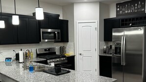 A modern kitchen with black cabinets, stainless steel appliances, and a granite countertop.