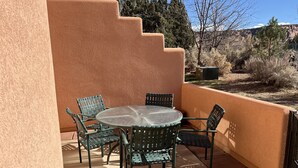 A patio with a round glass table and four chairs, surrounded by a stucco wall. - Dog Friendly 2B/2Ba Townhome near Moab Golf Course (Moab)