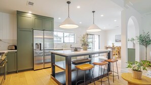 Een moderne keuken met een centraal eiland, krukken en hanglampen.