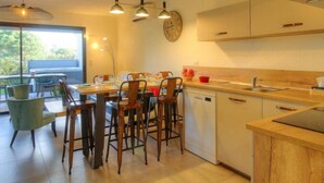 Een moderne keuken met een eethoek, houten kastjes en hangende lampen.