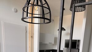 A modern kitchen with white cabinets, a black countertop, and stainless steel appliances. There is a dining area with a wooden table and black chairs. - Charmant Appartement (Angoulême)