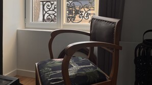 A room with a wooden chair by a window with a view of a balcony. - Charmant Appartement (Angoulême)