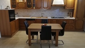 Una cocina con armarios de madera, una mesa de comedor con cuatro sillas y un horno empotrado.