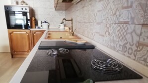 Una cocina con encimera negra, estufa integrada, un lavamanos y azulejos decorativos en la salpicadura.
