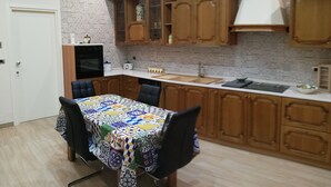 Una cocina moderna con armarios de madera, horno empotrado y una mesa de comedor con mantel colorido.