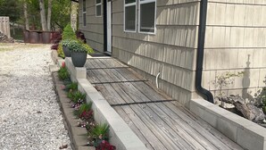 A house with a wooden deck, a front door, and a window. - Whiskey Barrel Bunkhouse (Sunrise Beach)