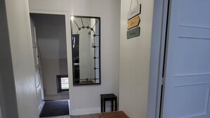 Ein Flur mit Teppichmuster, einem Spiegel, einem kleinen Tisch und einer Tür.