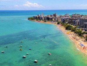 Un paisaje urbano costero con playa, aguas turquesas cristalinas y numerosos barcos.