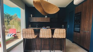 Una cocina moderna con armarios de madera oscura, una isla central con taburetes altos y una lámpara colgante.