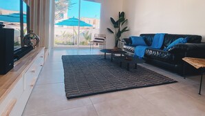 Una sala de estar moderna con un sofá de cuero negro, una mesa de centro y un ventanal con vistas a un jardín.