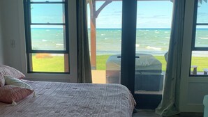 Un dormitorio con cama, vistas al océano y un patio con mesa y sillas.