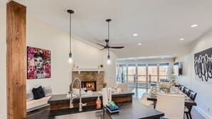 A modern kitchen with a central island, a stone fireplace, and a dining area with a view.