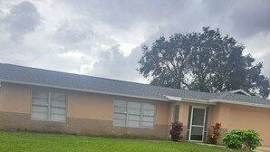 A single-story building with a flat roof, a brick foundation, and a large front lawn.