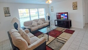 A living room with a sofa, coffee table, TV, and a ceiling fan.