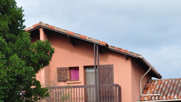 A two-story building with a brick facade, wooden balconies, and a brick wall in the foreground. - Appart. T3 au Port de Capbreton, Espace Piétonnier, 800m Plage et Centre Ville (Capbreton)
