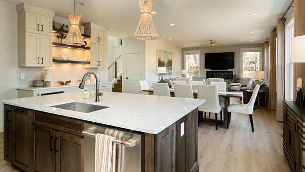 A modern kitchen with a large island, white cabinetry, and a dining area with white chairs. - The Haven on Hibiscus (Greer)