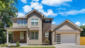 A two-story house with a garage, a covered porch, and a well-maintained lawn. - The Haven on Hibiscus (Greer)