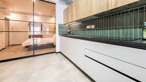 A modern kitchen with a wooden countertop, a sink, and a green backsplash.