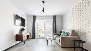 A modern living room with a sofa, coffee table, and TV on a wall.