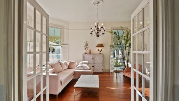 A spacious living room with a white sofa, a coffee table, and a chandelier.