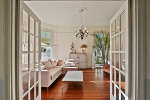 A spacious living room with a white sofa, a coffee table, and a chandelier.