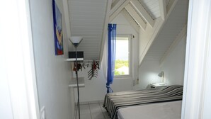 Une chambre à coucher avec un lit, une lampe, une fenêtre avec des rideaux et un tableau au mur.
