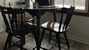 A dining area with a round table, four wooden chairs, a laptop, a coffee cup, and a metal water bottle. - Allegheny River House (Tidioute)