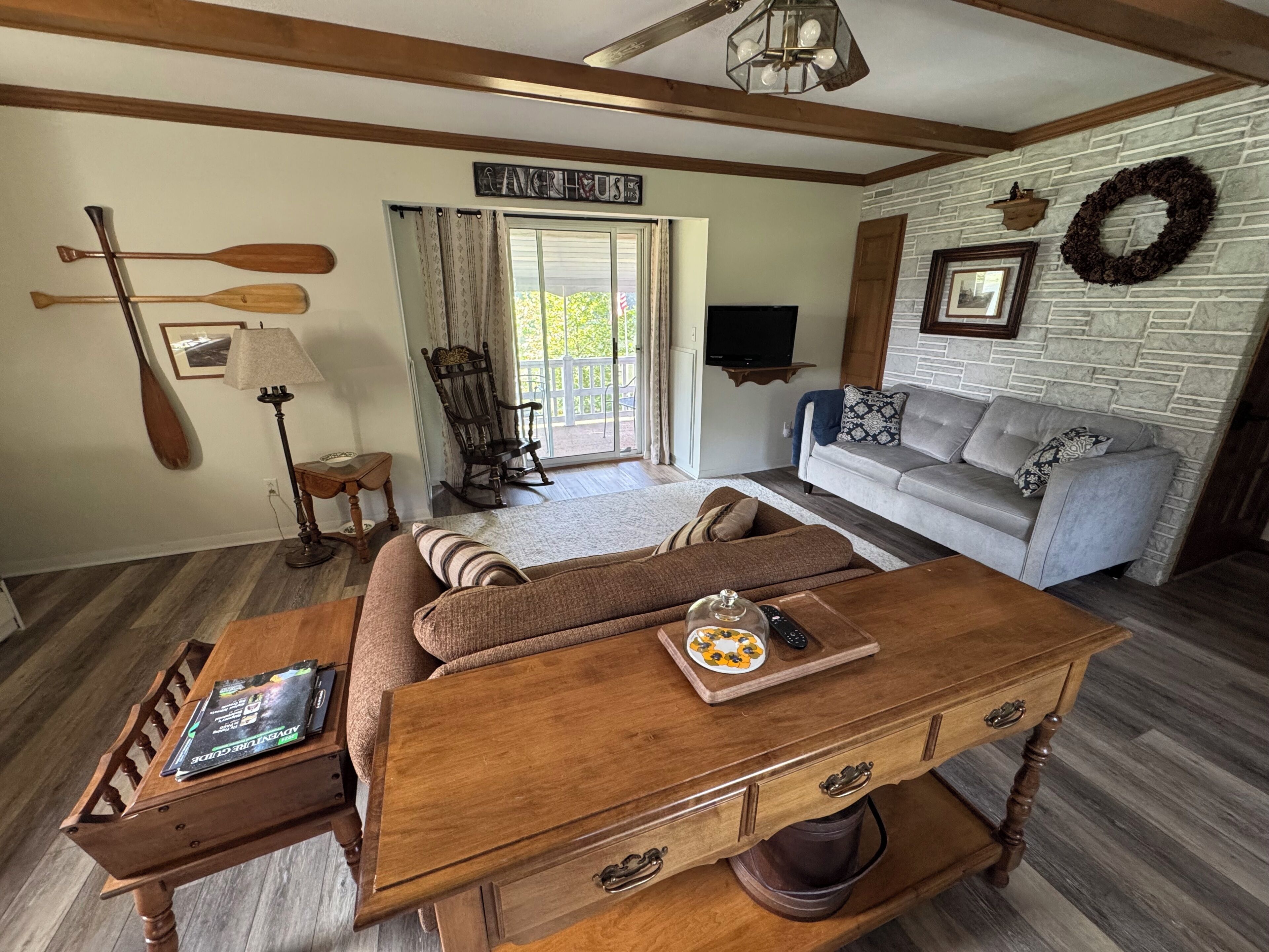 A cozy living room with a wooden coffee table, a sofa, a rocking chair, and a television.