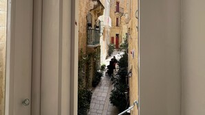 A narrow alleyway with buildings on either side, a clear sky, and a door frame. - Casa Norte (Birgu)