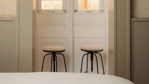 A bedroom with a bed, two stools, and a wardrobe with windows. - Casa Norte (Birgu)