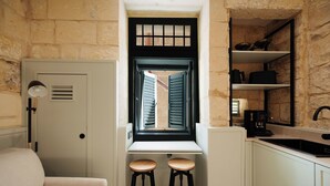 A compact kitchen with a window, two stools, a coffee machine, and a sink. - Casa Norte (Birgu)
