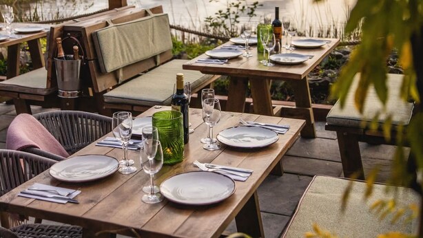 An outdoor dining area with tables set for a meal, overlooking a body of water. - Picturesque 5 Bed Cottage Lingfield, Surrey (Newchapel)
