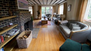 A cozy living room with a fireplace, a green sofa, and a wicker basket. - Picturesque 5 Bed Cottage Lingfield, Surrey (Newchapel)