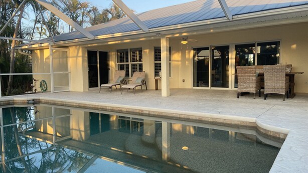A swimming pool with lounge chairs and a covered patio area. - The Island House on Pine Island
with heat-pump heated  most privacy pool (Bokeelia)