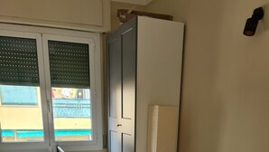 Makuuhuone, jossa on sänky, vaatekaappi, ikkuna ja patteri.