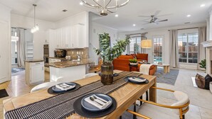 A modern kitchen with white cabinets, a dining area with a wooden table, and a ceiling fan. - Spacious 4BR/4.5BA, Pool & Heated Spa, Close Proximity to Dining, Shopping & Fun (Plano)