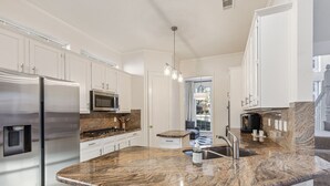 A modern kitchen with white cabinets, stainless steel appliances, a granite countertop, and a built-in oven. - Spacious 4BR/4.5BA, Pool & Heated Spa, Close Proximity to Dining, Shopping & Fun (Plano)