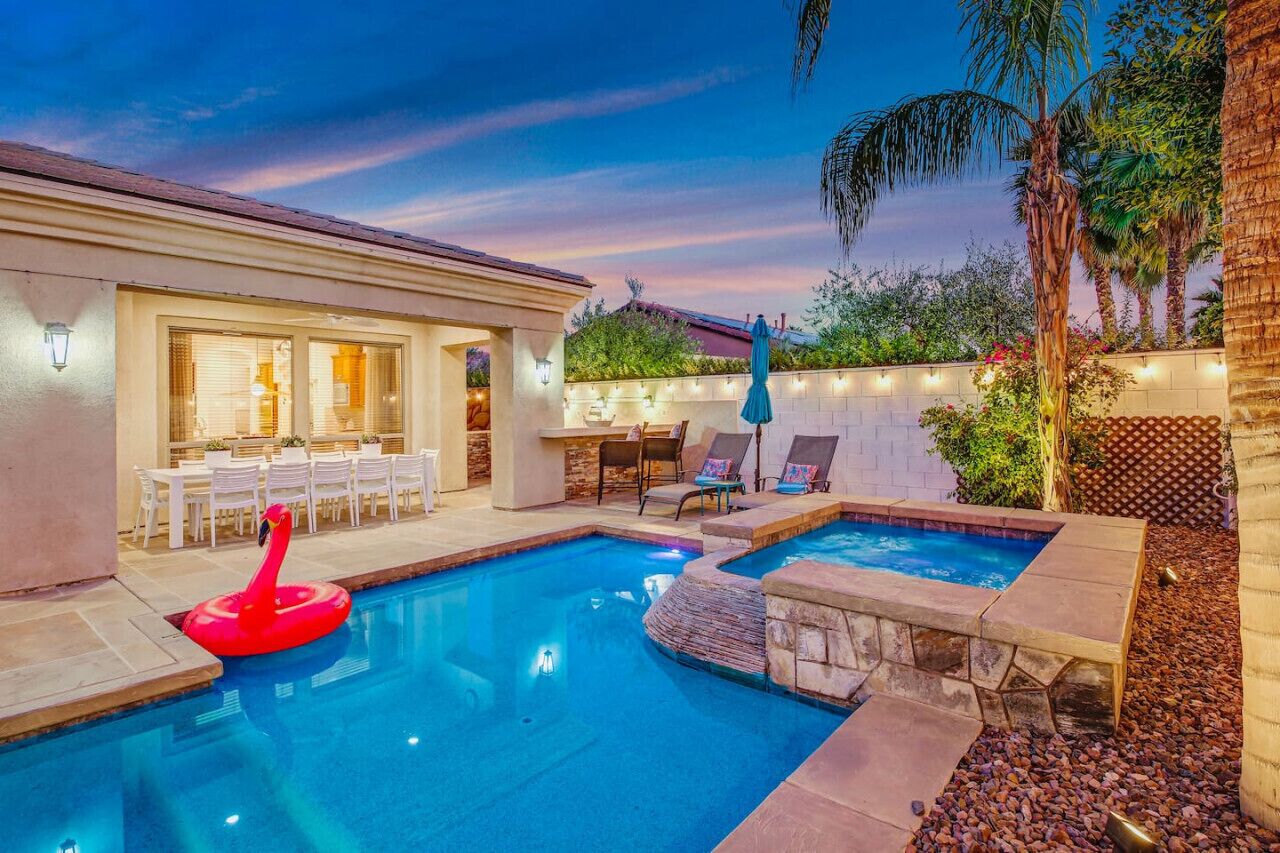 A backyard with a swimming pool, a dining area with outdoor furniture, and a tiki float.
