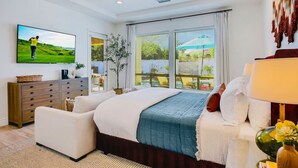 Une chambre avec un grand lit, un téléviseur fixé au mur, une commode et une fenêtre donnant sur un paysage verdoyant.