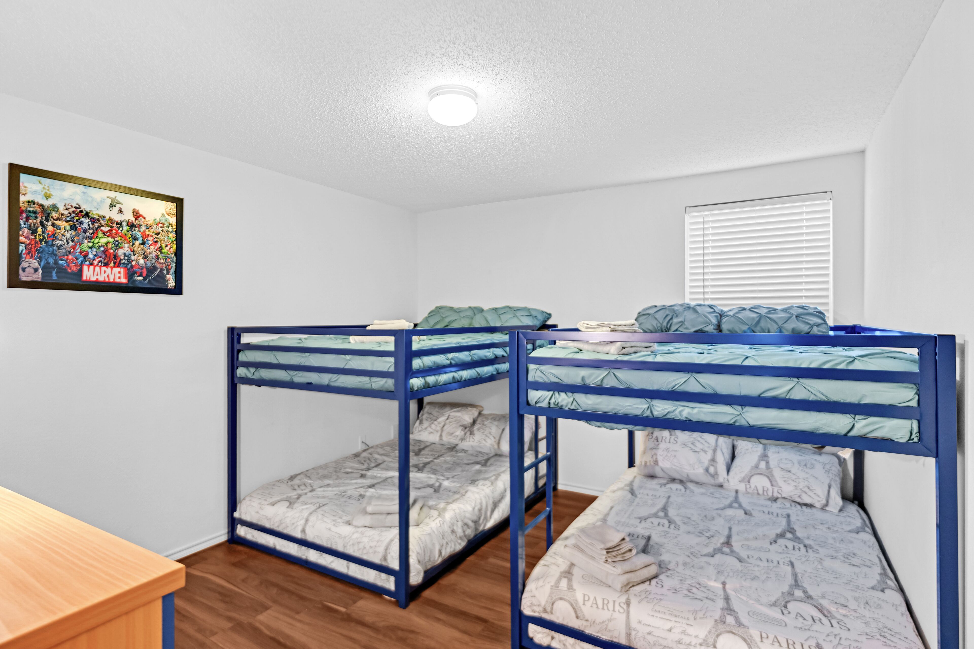 A room with bunk beds, a wooden desk, and a poster on the wall.