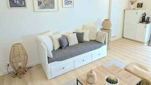 Ein gemütliches Wohnzimmer mit einem weißen Sofa, einem Holztisch und einer gewebten Stehlampe.