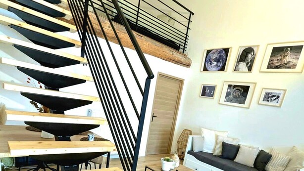 Ein modernes Wohnzimmer mit einer Holztreppe, einer Sofagarnitur und gerahmten Bildern an der Wand.