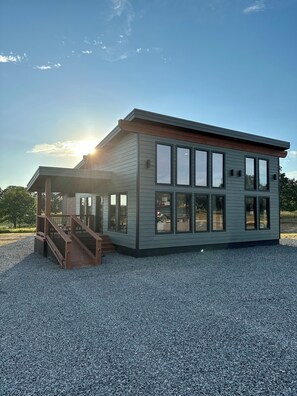 A modern building with a covered outdoor area and a gravel driveway. - Miss Behaving cabin (Broken Bow)