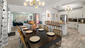 A modern kitchen with white cabinets, a central island, and a dining area with a dark wood table and chairs.