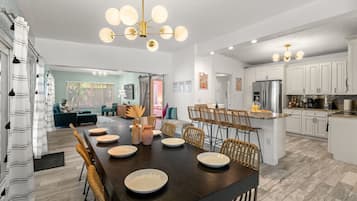 A modern kitchen with white cabinets, a central island, and a dining area with a dark wood table and chairs.
